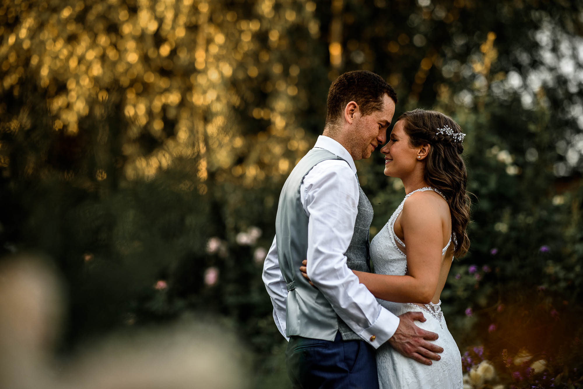 Amongst wild flowers bride and groom pose for natural portrait